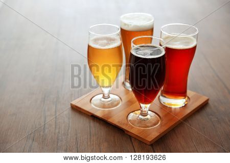 Glasses with different sorts of craft beer on wooden tray