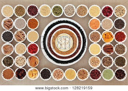 Large dried healthy superfood selection in china bowls forming an abstract background over hessian. High in antioxidants, vitamins, minerals and dietary fiber. 