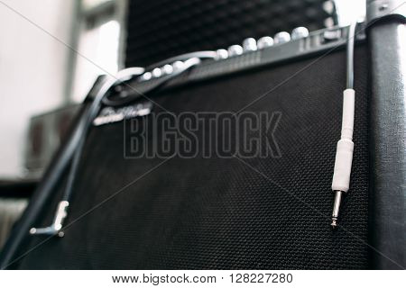 Electric guitar amplifier with silver knobs and cable closep. Selective focus technique on  professional guitar amplifier knobs