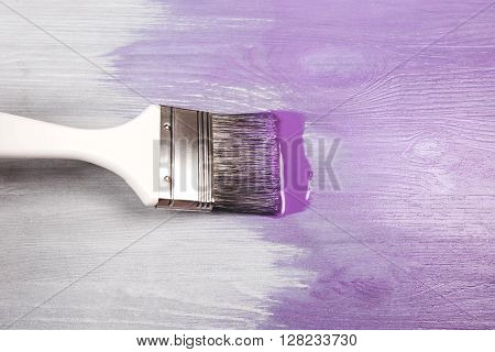 Painting white wooden surface with white paintbrush and violette of lavender color.