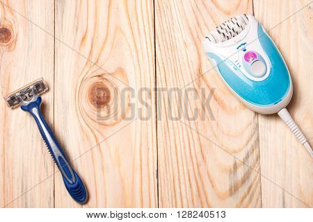 electric epilator with a razor on a light wooden background.