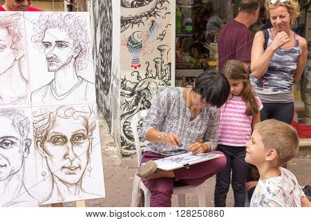 Tel Aviv, Israel - April 28, 2016: Street cartoonist draws a caricature surrounded by people in Tel Aviv, Isarel