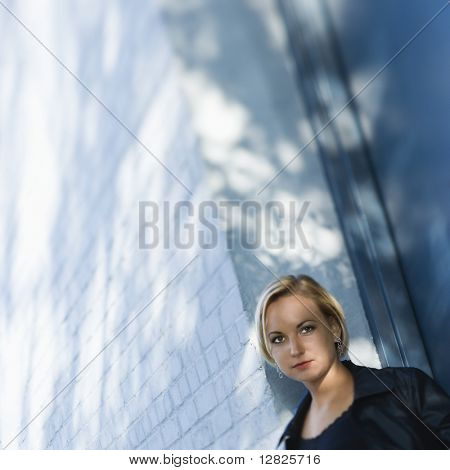 Indoeuropea males donna bionda in piedi contro sole screziata di costruzione guardando visualizzatore.