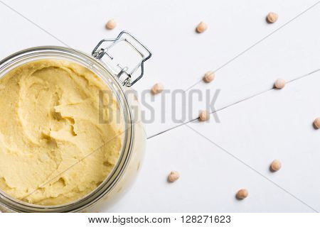 Homemade DIY natural vegan very healthy hummus of chickpeas in a glass jar on a wooden table
