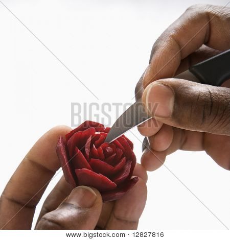 Afro-américaine mains mâles découpant une betterave rouge dans une rose.