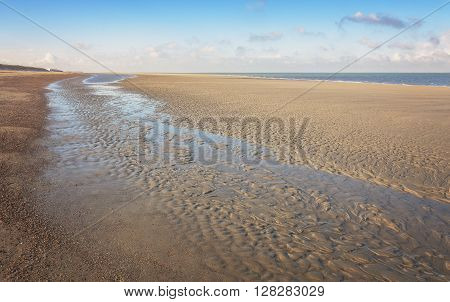 Low tide in the sea formed a small puddle and pattern in the sand.