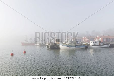 GRISSLEHAMN SWEDEN - MAY 01 2016: Small fishing boats in the harbor a foggy morning in Grisslehamn Sweden