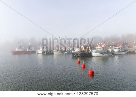 GRISSLEHAMN SWEDEN - MAY 01 2016: Small fishing boats in the harbor a foggy morning in Grisslehamn Sweden
