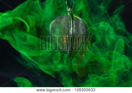 A tea ball with fluorescein in water. Fluorescein is a green fluorescent coloring agent for water.