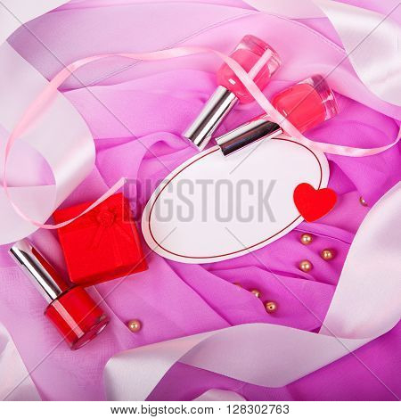 bottle of nail polish on a pink matter with white satin ribbons and sign for text