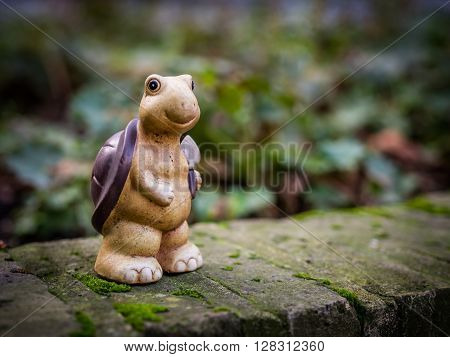 Small turtle figurine standing on a wall in the garden