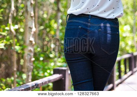 Rear view of Young Asia woman wearing jeans standing on walkway.