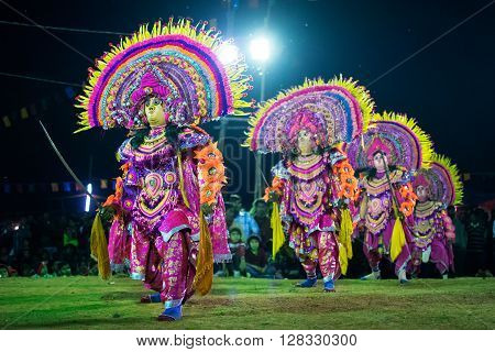 BAMNIA PURULIA WEST BENGAL INDIA - DECEMBER 23RD 2015 : Four masked dancers performing at Chhau Dance festival shot under colored lights. It is a very popular Indian tribal martial dance performed at night amongst spectators.