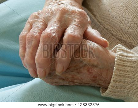 Elderly woman holding hand over other hand with arthritis