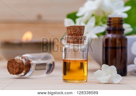 Bottle Of Essential Oil And Jasmin Flower With Shallow Depth Of Field Setup On Wooden Background .