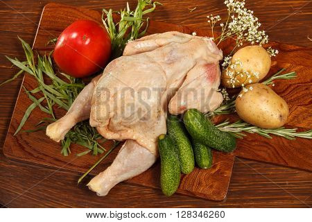 Raw chicken with vegetables on a wooden table