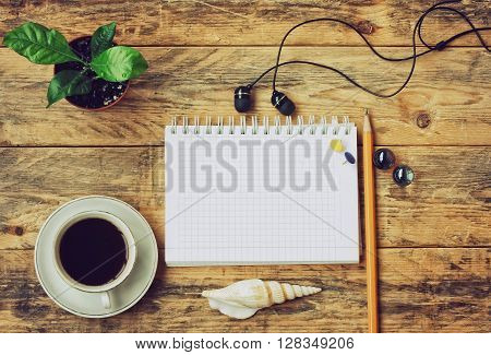 coffee cup headphones flower in pot seashell pen and notebook on wooden table top view