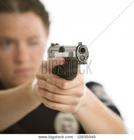 Close up di metà adulto femmina caucasica funzionario di polizia puntando la pistola alla spettatore con un occhio clo