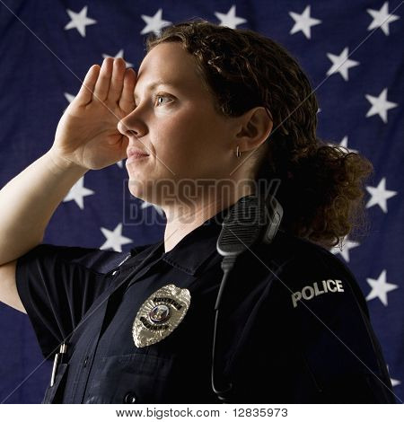 Ritratto di metà adulta poliziotta caucasica salutando con la bandiera americana come sfondo.