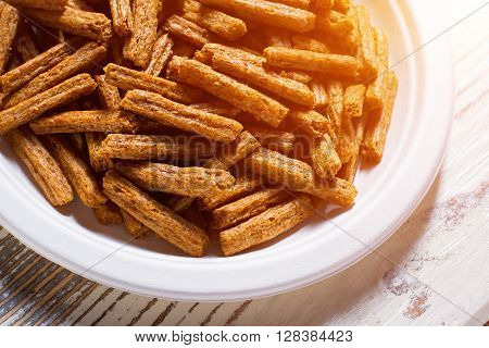 Pile of crackers on plate. White plate with bread crackers. Crispy sticks on white table. Simple snack recipe.