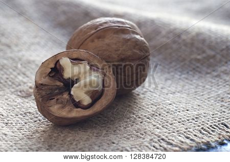 Walnut close-up near open walnuts close-up. Burlap on a black wooden table. Horizontal shot.