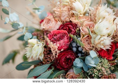 Beautiful wedding colorful bouquet for bride against nature background close-up macro shot. Beauty of colored flowers. Bridal accessories. Female decoration for girl. Details for marriage and for married couple
