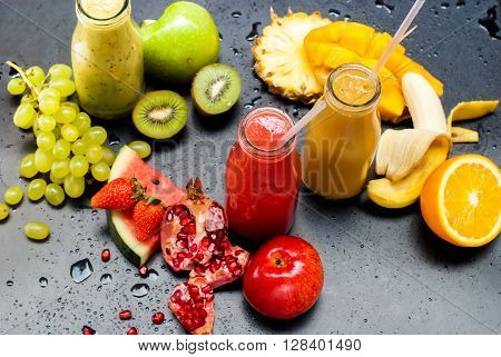 Fresh Juices Smoothie Three Bottles made Red Green Orange Fruits Water Melon Strawberry Apple Kiwi Grapes Orange Mango Pomegranate Tropical Selective focus Black Background