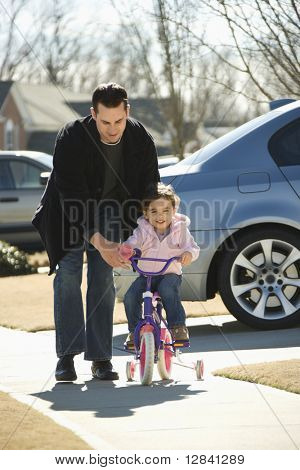 Кавказский отец, помогая дочь ride велосипед.