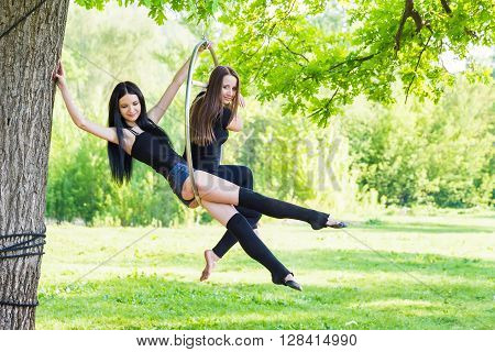 Two beautiful girls on the hoop on nature background