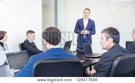Successful team leader and business owner  leading informal in-house business meeting. Businessman working on laptop in foreground. Business and entrepreneurship concept.