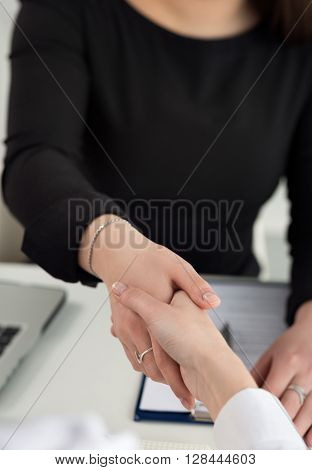 Two women handshake in office closeup. Businesswomen shaking hands. Serious business partnership and collaboration concept. Partners made deal and sealed it with handclasp. Formal greeting gesture
