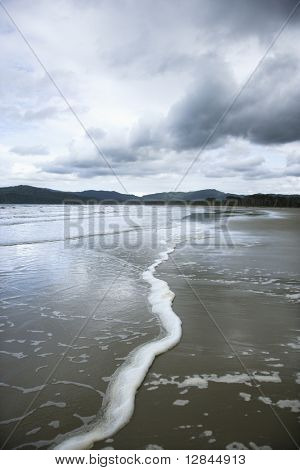 Oceano con montagne lontane e cielo nuvoloso nella foresta pluviale di Daintree, Australia.