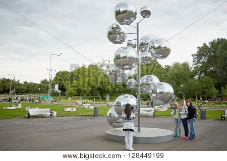 MOSCOW, RUSSIA - JUN 29, 2015: People walk in Gorky park near tree made of metal rod and mirror inflatable balls. The total area of the park is 219.7 hectares.
