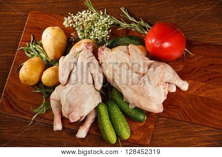 Raw chicken with vegetables on a wooden table