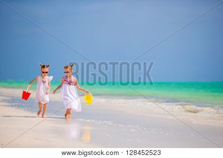 Adorable little girls have fun on white beach during vacation
