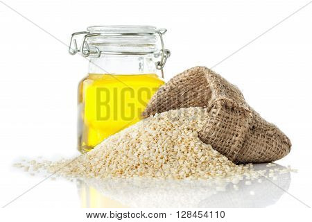 Sesame oil in a transparent glass jug and sesame close-up isolated on white background