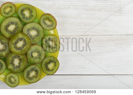 Dish full of kiwi slices on wooden surface with copy space. Top view composition. Helping digestion with enzymes. Boosting immunity. Creating alkaline balance. Naturally organic food. Premier Antioxidant Protection.