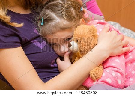 Little Girl With A Teddy Bear Clung To Her Mother With A Sad Expression On His Face