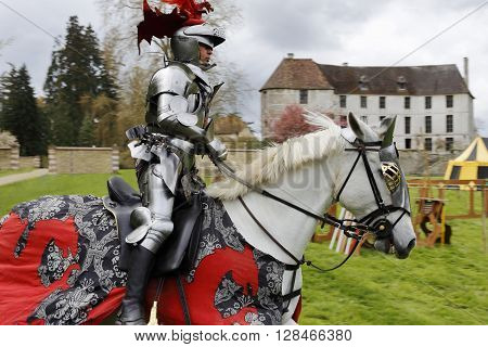 Harcourt France - April 23 2016: An unidentified man in a suit of armour is riding his horse to a mediaeval jousting tournament on Apr. 23 2016 in Harcourt France. It takes place in front of the castle Harcourt in Harcourt France