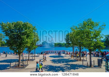 HAMBURG, GERMANY - JUNE 08, 2015: Big bote with people walking around stops at Binnenalster lake, in the center of Hamburg. Splash water behind