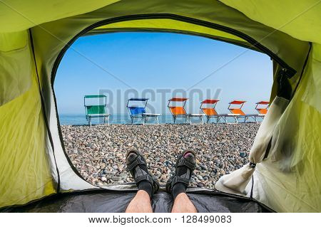 View from inside a tent on the colorful beach chairs on the shingle beach near sea
