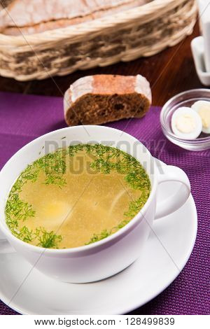hot fresh soup with eggs and dill in white dish
