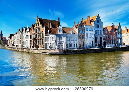 Bruges, Belgium - April 10, 2016: Panorama with canal and colorful traditional houses against cloudy blue sky in popular belgian destination, Brugge, Belguim