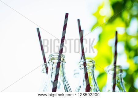 Glass Bottles With Straws Over The Sunny Background