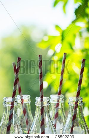Glass Bottles With Straws Over The Sunny Background
