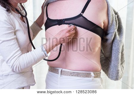 female doctor is listening to lunge of female patient