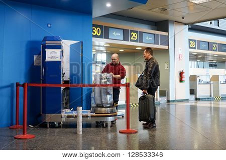 VALENCIA, SPAIN - MAY 5, 2016: An airline passenger having his luggage wrapped in industrial strength cling film. Wrapping your luggage in cling film can provide peace of mind ahead of your journey.