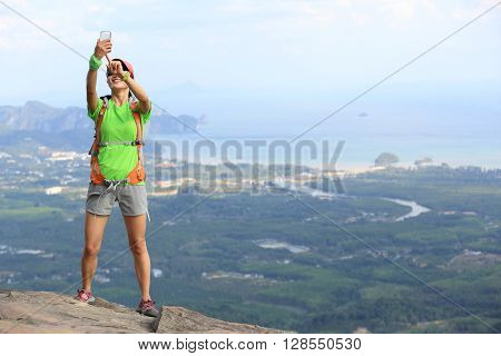 young woman hiker use smartphone taking photo on seaside mountain top