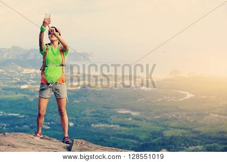 young woman hiker use smartphone taking photo on seaside mountain top