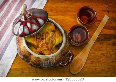 On a black table there is a blue baking dish potato and meat. A dish ready stewed potato with meat